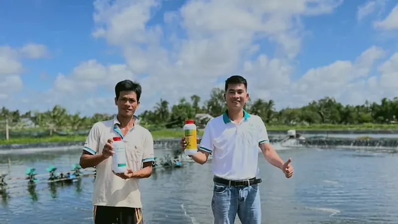 Kỹ sư Thần Vương và người nuôi tại bờ ao, quạt nước đang chạy phía sau